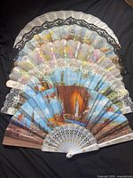 All four folding souvenir fans displayed open, showing designs and lace edges