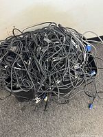 Two storage bins filled with tangled black AC cords, VGA cables and assorted electronics