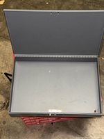 Open gray metal lock box, empty interior visible
