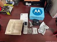All items laid out: phone, battery, charger, manual, holster, packaging tray, box