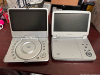 Both DVD players open showing screens and control layouts