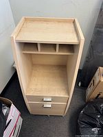 Front view of light maple/birch plywood cabinet showing top shelf, cubbies, two drawers, and casters