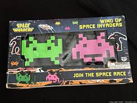 Front of box showing both green and pink wind-up figures through window