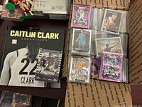 Caitlin Clark book, football card, stacks of sleeved basketball cards inside box