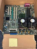 Top view of complete motherboard in box showing heatsinks, fans, RAM, expansion slots and handwritten note