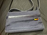 Front view showing canvas body, leather trim, logo plaque, strap
