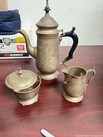 Coffee/teapot, sugar bowl with lid, creamer on wooden surface