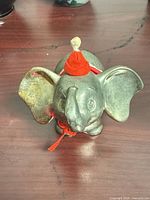 Front view of pewter elephant coin bank with red felt hat