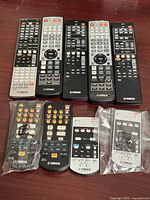 Nine Yamaha remote controls laid out on tabletop