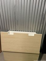 Front view showing light wood veneer panel and recessed handle