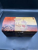 Front angled view closed showing café motif on lid and latch