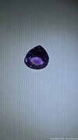 Pear cut deep purple amethyst displayed on neutral background