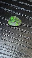 Triangular Australian matrix opal cabochon showing green flash on dark matrix