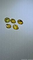 Five yellow oval gemstones on light background