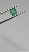 Emerald held in tweezers, angled top view