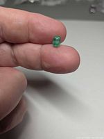 Emerald held between fingers showing size and color