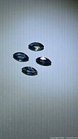 Four marquise faceted sapphires on neutral surface showing blue-green color