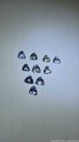 Ten trillion-cut tanzanite gemstones laid out on neutral background