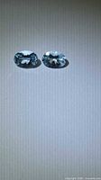 Pair of oval-cut pale blue aquamarines on neutral background