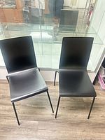 Front view of both black plywood chairs with metal legs