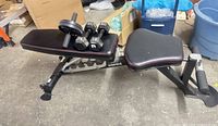 Side view of Inspire bench with dumbbells and ab roller on seat