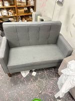 Front view of light grey loveseat showing button-tufted back and seat