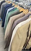 Row of assorted men’s blazers on wooden hangers