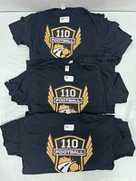 Stack of folded black T-shirts showing front crest logo