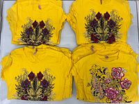 Stacks of yellow rhinestone graphic T-shirts, both designs visible