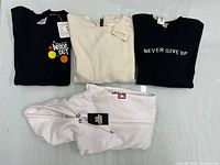 All four sweatshirts laid out showing fronts and tags