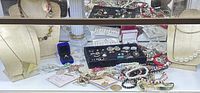 Glass case view showing necklaces on busts, rings, earrings tray, loose jewelry and displays