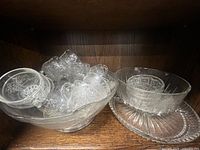Large punch bowl containing multiple handled cups alongside oval platter and serving bowl