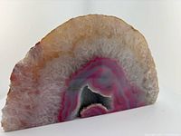 Front view of semi-circular dyed pink agate slab showing bands and druzy center
