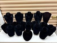 Front view of all 17 black velvet necklace stands arranged in two rows.