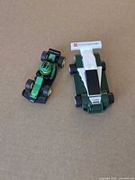 Both green LEGO racecars side by side on plain surface