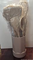 utensils set standing in beige holder wrapped in plastic