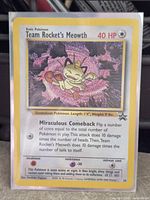 Front view of Team Rocket's Meowth promo card in sleeve