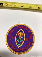 Front view of round embroidered patch showing full design and ruler indicating size