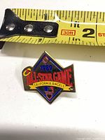 Front of diamond-shaped enamel lapel pin next to tape for scale