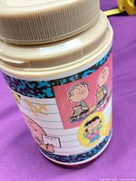 Side view of jar showing Peanuts character wrap and beige lid