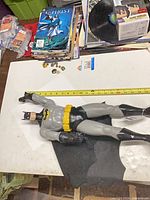 Full view of Batman figure beside tape measure showing length