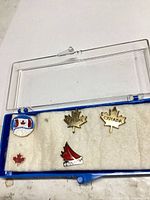 Open display case showing five Canadian lapel pins on foam insert