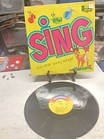 Front cover showing title and characters; vinyl displayed below
