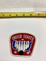 Front view of embroidered United States map patch with measuring tape showing size