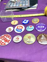 Group shot of all visible pinback buttons with measuring tape for scale