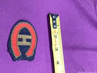 Front view of embroidered Montreal Canadiens patch beside tape measure showing height just over 2 inches