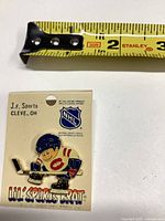 Front of pin on backing card with tape measure showing size
