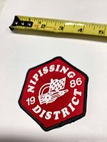 Front view of patch near measuring tape showing size and design