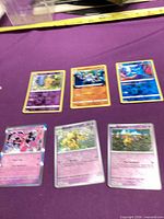 All six Pokémon cards laid out on purple surface