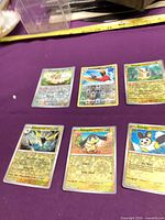 Six Pokémon reverse-holo cards laid out on purple surface
